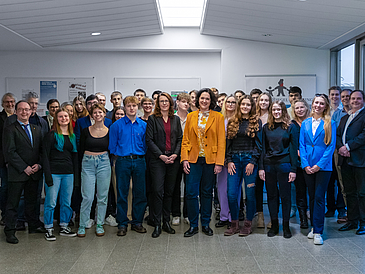 The picture shows a group of around 30 pupils. They are standing together with Katrin Moosdorf, Senator for Environment, Climate & Science and Dr. Mandy Boehnke, Vice-Rector for Internationality, Academic Qualification and Diversity at the University of Bremen, Mandy Böhnke.